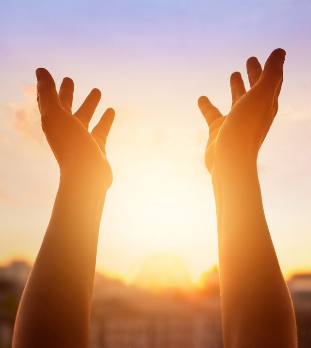 Human respecting and praying on sunset in the city background